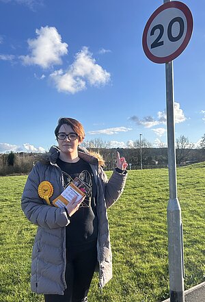 Liberal Democrat Candidate Sara Allmark pointing at a 20mph sign